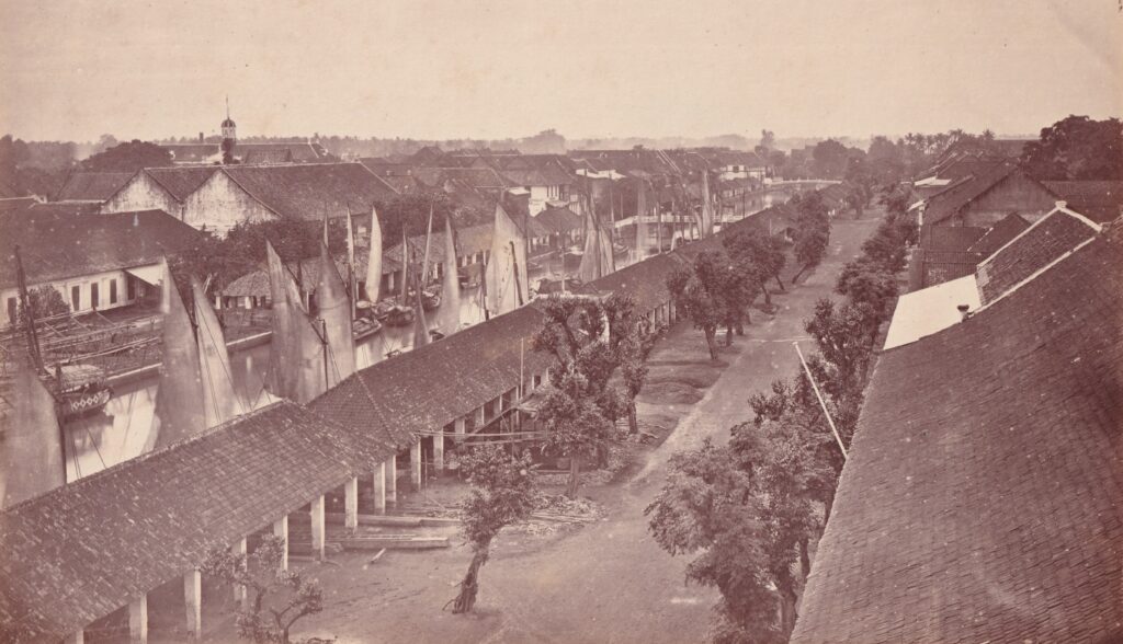 This photograph of Kali Besar, taken around 1870 by the photostudio Woodbury & Page, captures a bustling scene from the Kali Besar. Traditional sailing vessels are moored along the canal, flanked by warehouses. While most of the buildings in the image no longer exist, the shophouses on the right still stand today. On the left, the distinctive tower of the Stadhuis van Batavia (Batavia City Hall) rises above the rooftops. The historic building now houses the Fatahillah Museum. (Sake Santema Collection)